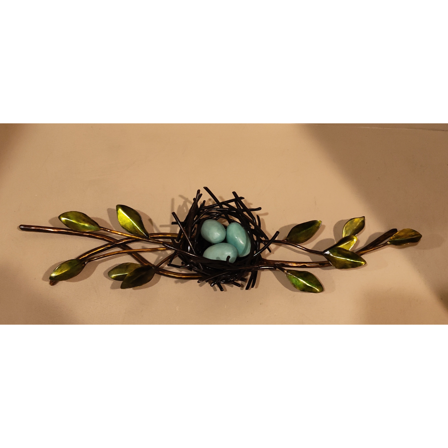 Metal sculpture with leaves and a robin's nest with three eggs inside
