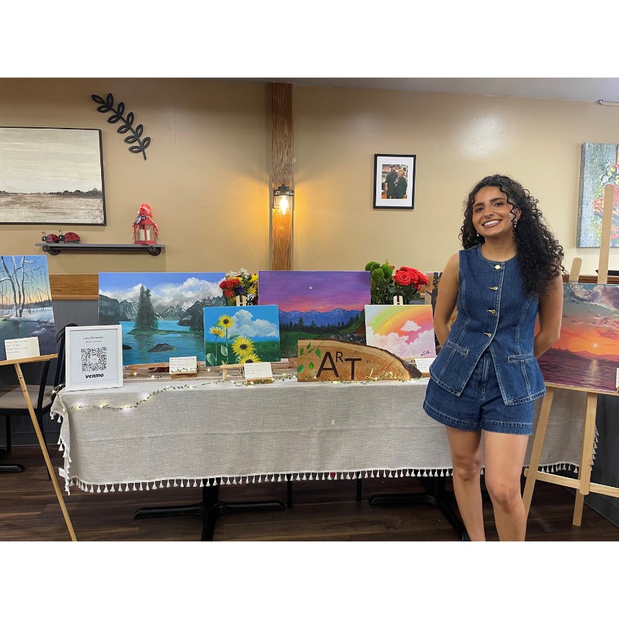 Artist with canvas paintings displayed on table