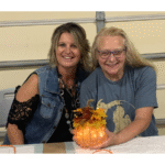 Photo of two women holding a hand-crafted fabric pumpkin glowing with lights inside